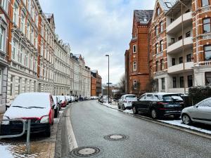 Exklusive Apartments in Kieler City في كيل: شارع مغطى بالثلج مع سيارات تقف على جانب الطريق
