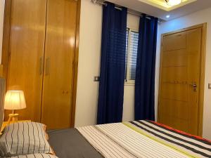 - une chambre avec un lit et une fenêtre avec des rideaux bleus dans l'établissement Dar sammoud S+1, à Kelibia