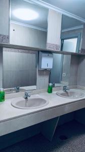 Baño público con 2 lavabos y espejo en Hostel 165, en Madrid