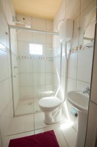 a white bathroom with a toilet and a sink at Pousada Jomar in Xangri-lá