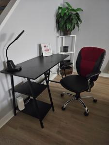 a black desk with a red chair and a lamp at Newly Renovated Suite in Regina