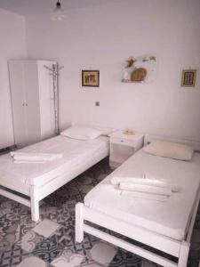 three beds in a room with white walls at Kalymnos Platy Gialos Mousellis Makis Apartments in Kalymnos