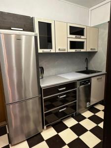 a kitchen with a stainless steel refrigerator and a checkered floor at Apartament 70’s in Kołobrzeg +5 photos