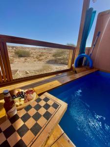 a chess board on a table next to a swimming pool at Zman Arava in Zuqim