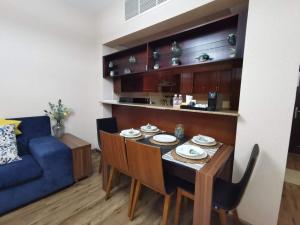 a living room with a table and a blue couch at Adar Homes 2 - شقة غرفتين نوم مطلة على البحر in King Abdullah Economic City