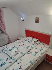 a bed with a red headboard in a bedroom at Cabana Cosmina &Milan in Cîmpeni