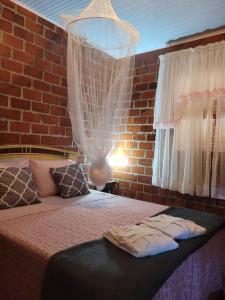 ein Schlafzimmer mit zwei Betten und einer Ziegelwand in der Unterkunft Casa de campo em Carlos Barbosa - Serra Gaúcha in Carlos Barbosa