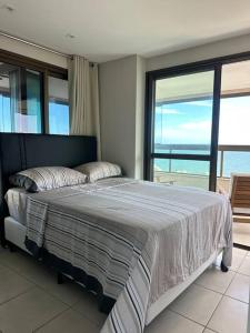 um quarto com uma cama e vista para o oceano em Apartamento Total Vista do Mar. em Salvador
