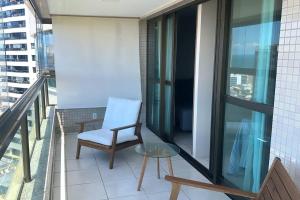 uma varanda com uma cadeira e uma mesa de vidro em Apartamento Total Vista do Mar. em Salvador