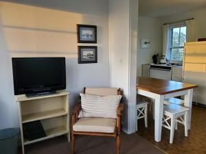 uma sala de estar com uma televisão e uma mesa com uma cadeira em Barrington Inn Barn em New Shoreham