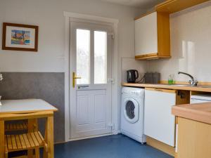 a kitchen with a washing machine and a window at Cedar Cottage - Uk32633 in Grantown on Spey