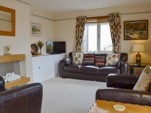 a living room with leather couches and a tv at Cedar Cottage - Uk32633 in Grantown on Spey
