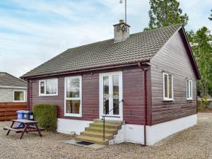 a small red and white house with a picnic table at Cedar Cottage - Uk32633 in Grantown on Spey