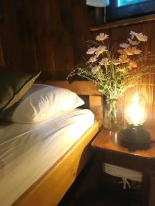 Una cama con un jarrón de flores y una lámpara en Countryside cottage with mountain view, en Lukovica pri Domžalah