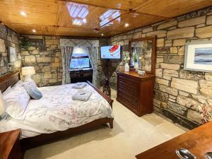 Habitación con paredes de piedra, cama y TV. en Tennox Stables - Uk39975 en Kilbirnie