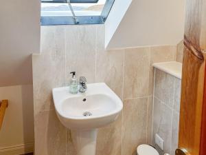 lavabo blanco en un baño con ventana en The Fishermans Cottage en Applecross