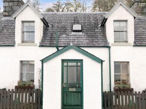 una casa bianca con una porta verde e una recinzione di The Fishermans Cottage ad Applecross