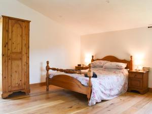 Schlafzimmer mit einem Holzbett und einem Holzschrank in der Unterkunft Slade Barn - Uk42977 in Highbray