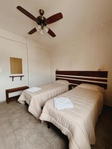 two beds in a room with a ceiling fan at Mareas II in Esquina