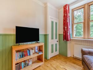 a living room with a flat screen tv on a book shelf at Gardeners Cottage in Huntly