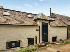 una vieja casa blanca con una puerta negra en Craigdarroch Cottage, en St Fillans