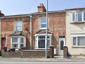 a red brick house with a white front door at Newstead Cottage in Weymouth