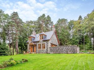 a large house on a grassy field with trees at Gardeners Cottage in Huntly