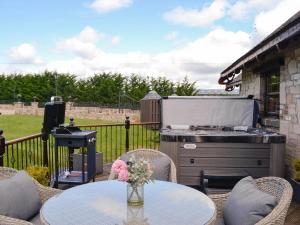 d'une terrasse avec un barbecue, des tables et des chaises. dans l'établissement Tennox Boathouse - Ukc4438, à Kilbirnie