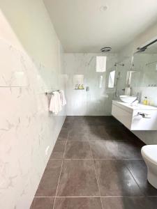 a white bathroom with a toilet and a sink at Risby Cove Boutique Hotel in Strahan