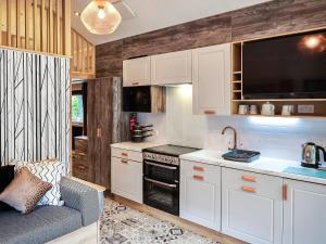 a kitchen with white cabinets and a couch in a room at Forest Escape - Uk7813 in Coirantee