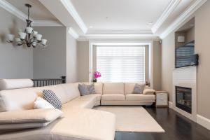 sala de estar con sofá blanco y chimenea en Rare Find Exquisitely New Quiet & Safe Skytrain Home, en Vancouver