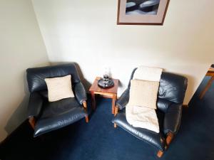 two black leather chairs and a table in a room at Risby Cove in Strahan