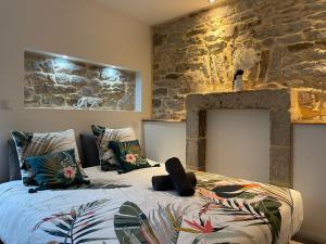 a bedroom with a bed and a stone wall at LE CALLOCH 2D - Studio 4 Étoiles - Quartier Gare - Wifi - Netflix in Quimper