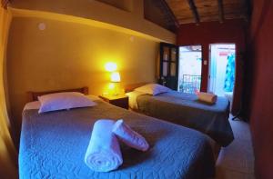 a hotel room with two beds with towels on them at B&B Sun Gate in Ollantaytambo