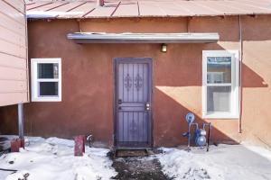 a house with a blue door in the snow at Studio Casita-15 min walk to Downtown Plaza in Santa Fe