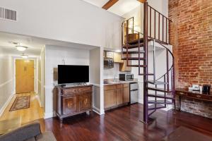 a living room with a staircase and a television at Maison Pierre Lafitte in New Orleans