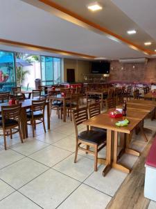 a dining room with wooden tables and chairs at Golden Lake Apart Hotel Arraial do Cabo RJ A&J in Arraial do Cabo