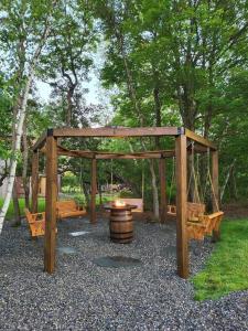 a wooden gazebo with a barrel in a park at Entire cottage, Firepit, BBQ, in & out pool access in Long Pond