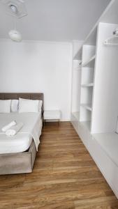 a white bedroom with a bed and shelves at Seasons Apartment's Vlora in Vlorë