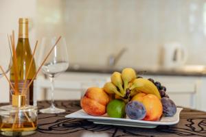 a plate of fruit on a table with a bottle of wine at Palma Apartments in Herceg-Novi