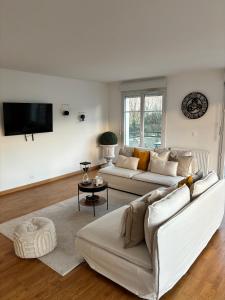 a living room with two white couches and a tv at Somptueux Appart' Aux Portes de Disneyland in Serris