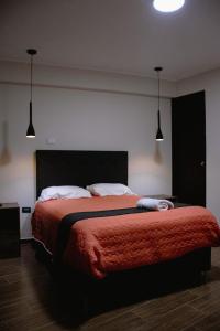 1 dormitorio con 1 cama grande con manta roja en PRANA HOTEL LOUNGUE BAR, en Huancayo