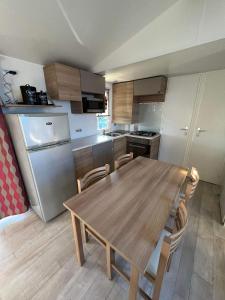 a kitchen with a wooden table and a refrigerator at mobilhome 6/8 pers. camping siblu les charmettes in Les Mathes