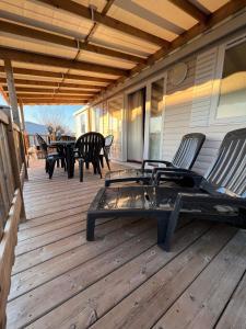 a deck with chairs and tables on a house at mobilhome 6/8 pers. camping siblu les charmettes in Les Mathes