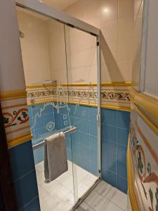 y baño con ducha de cristal y azulejos azules. en Mansion Tepotzotlan, en Tepotzotlán