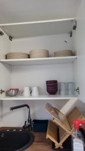 a kitchen with a sink and a shelf with dishes at L'agréable in Nantes