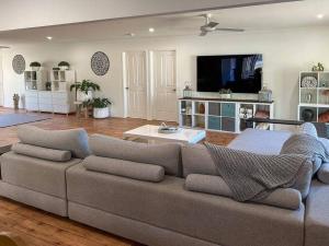 sala de estar con sofá y TV de pantalla plana en Balmurray House, en Ballandean