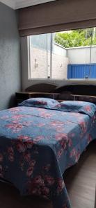 - une chambre avec un lit doté d'un couvre-lit floral et d'une fenêtre dans l'établissement Apartamento inteiro com área e garagem privativa, à Belo Horizonte