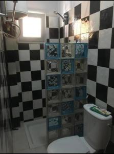 a bathroom with a toilet and a checkered wall at Cosy appart F3 à liberté 6 extension in Dakar