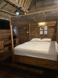 Bett in einem Zimmer mit Holzwänden und einer Decke in der Unterkunft Pucuk Bali Homestay in Canggu